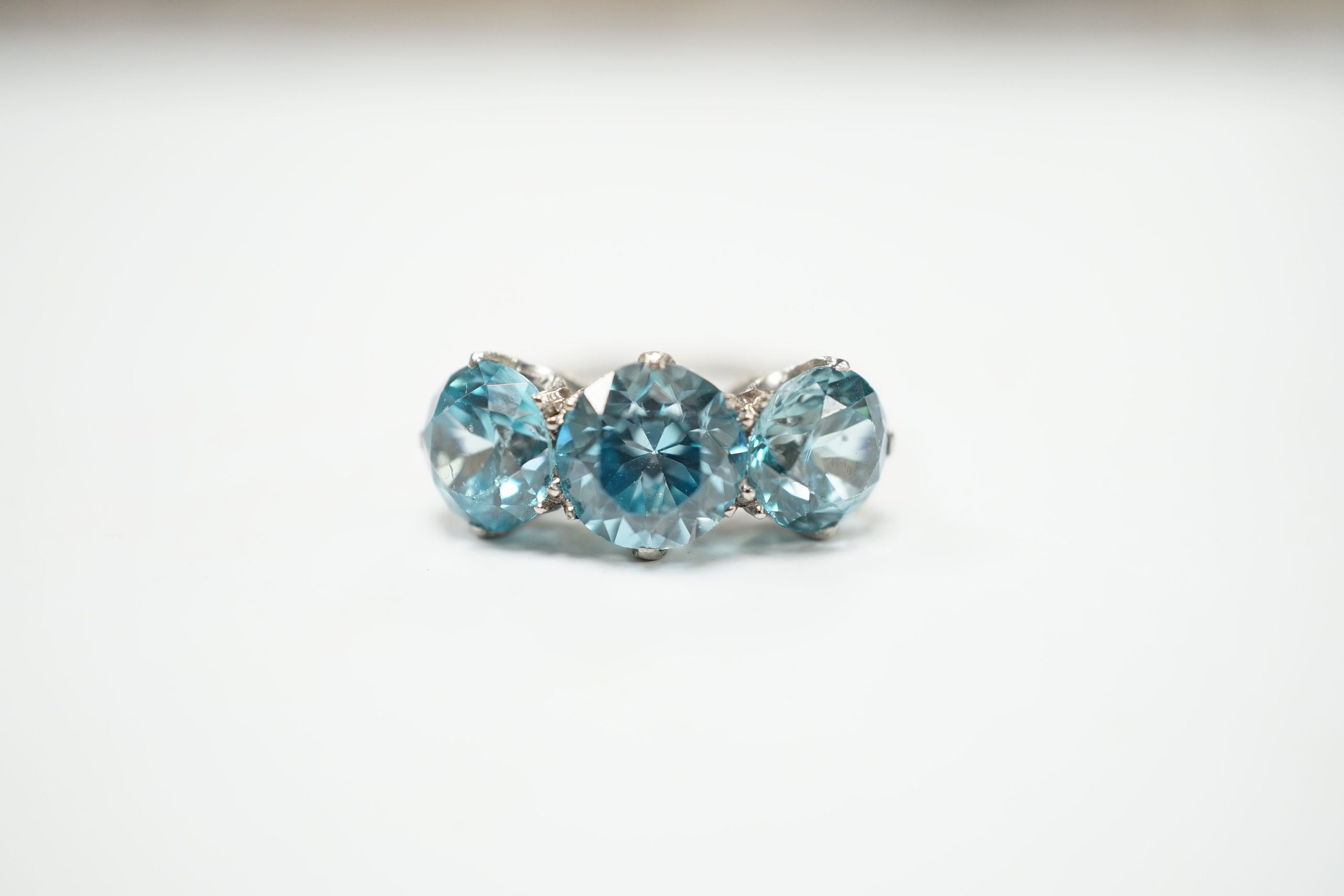 A white metal and three stone blue zircon set dress ring, size L, gross weight 4.1 grams.